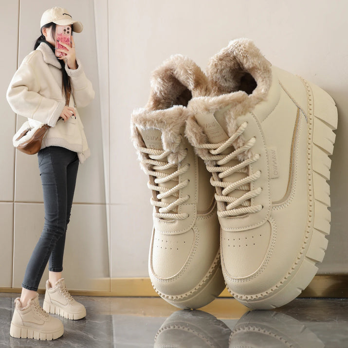 Beige winter boots with fur lining on a reflective surface, with a person wearing similar boots in the background.