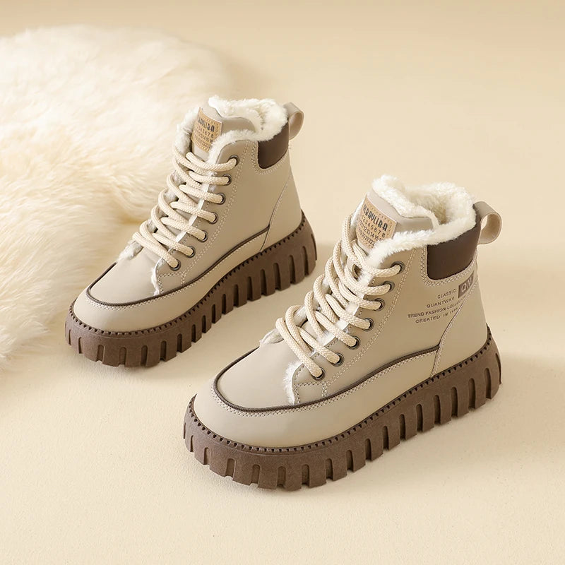 Pair of white winter boots with brown soles on a beige background