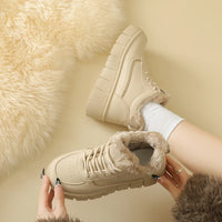 Beige winter boots with fur lining worn by a person on a beige background