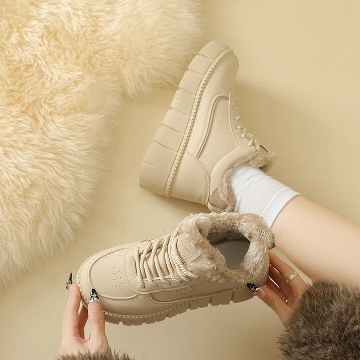 Beige winter boots with fur lining worn by a person on a beige background