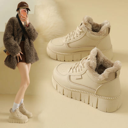 Beige winter boots with fur lining worn by a person on a beige background