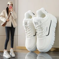 White sneakers with black accents on a reflective surface, next to a person wearing similar shoes indoors.